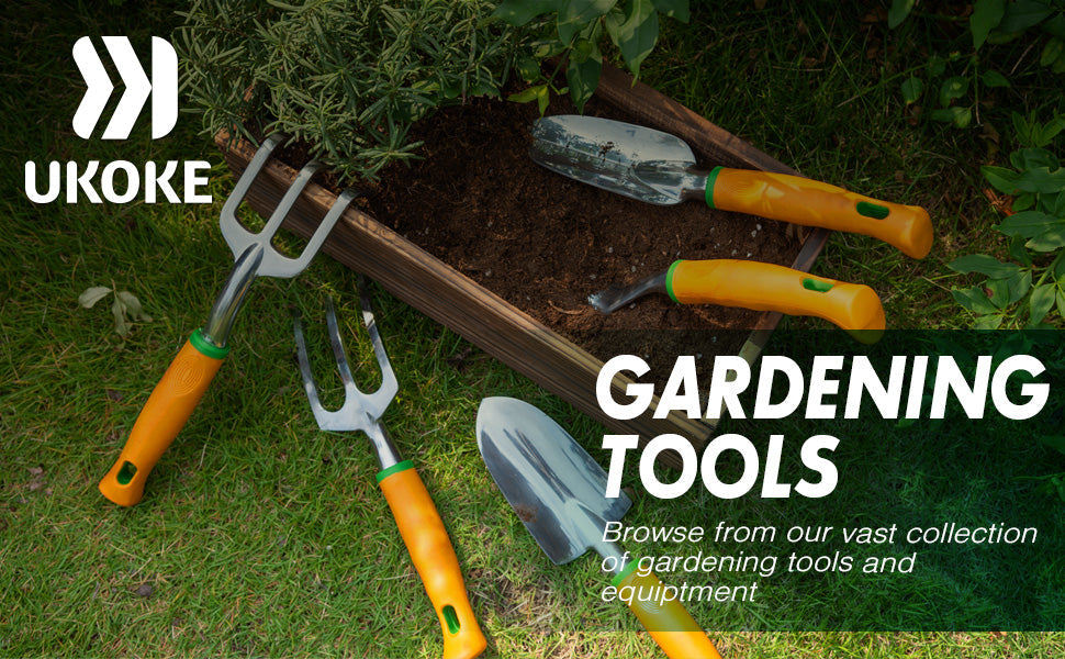 Gardening tools with orange handles on grass and soil near a raised garden bed