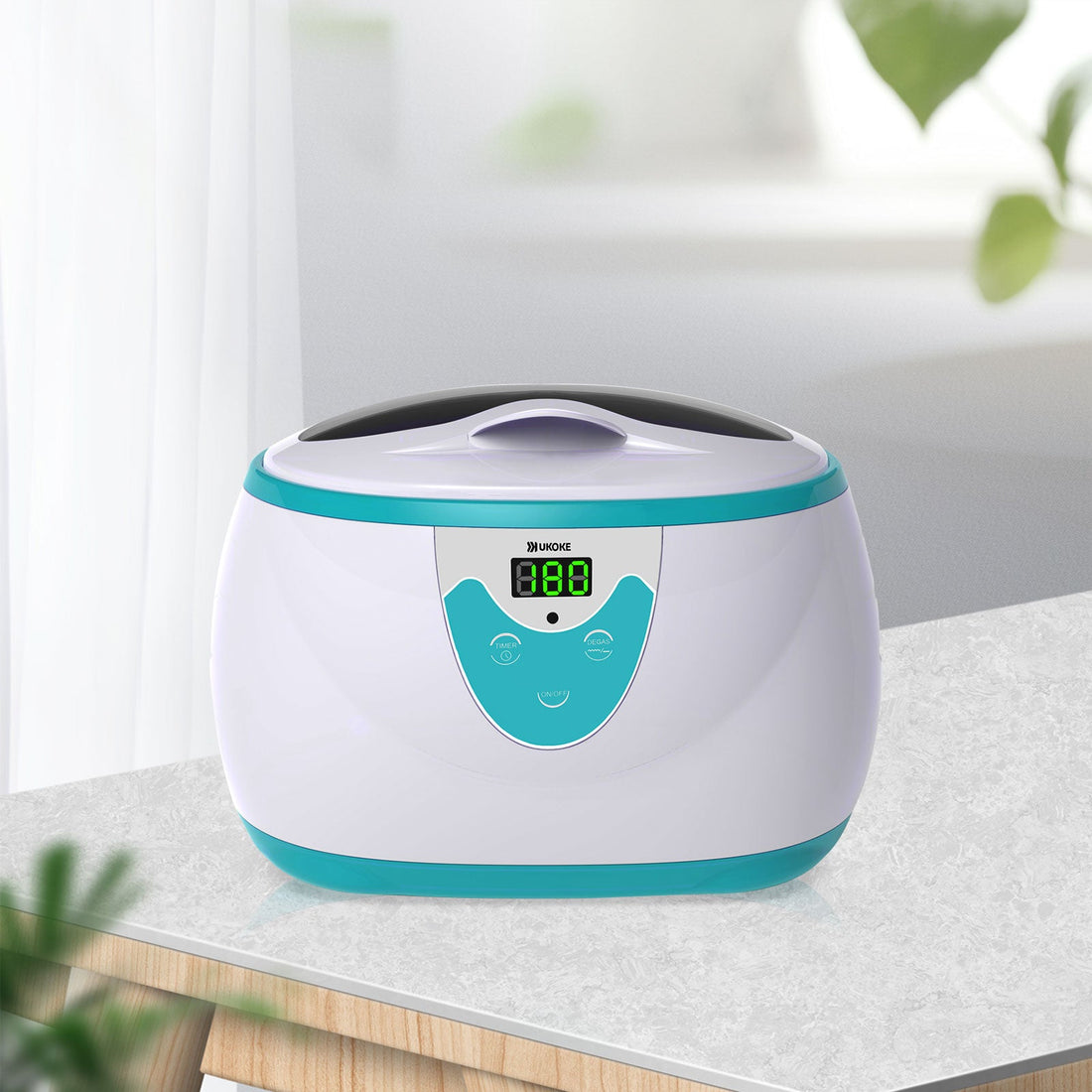 Digital ultrasonic cleaner with teal accents on a countertop in a bright room