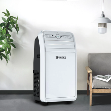 Portable air conditioner in modern living room with a chair, plant, and lamp nearby.