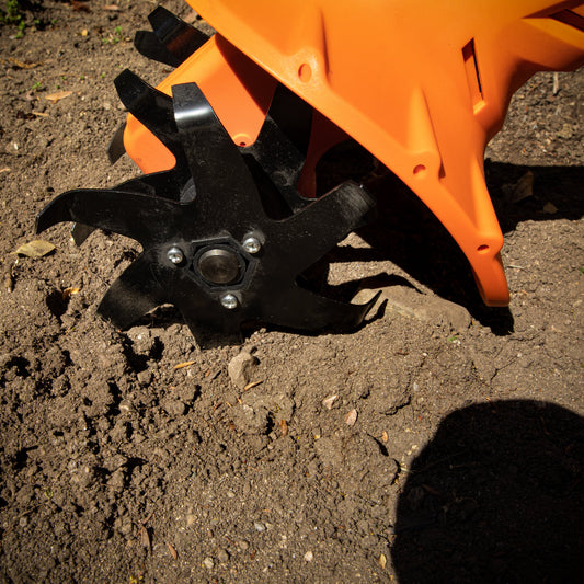 Close-up of rotary tiller blade cultivating soil in a garden