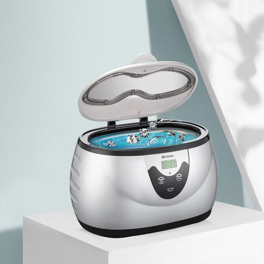 Ultrasonic jewelry cleaner with digital display cleaning rings and earrings on a white table